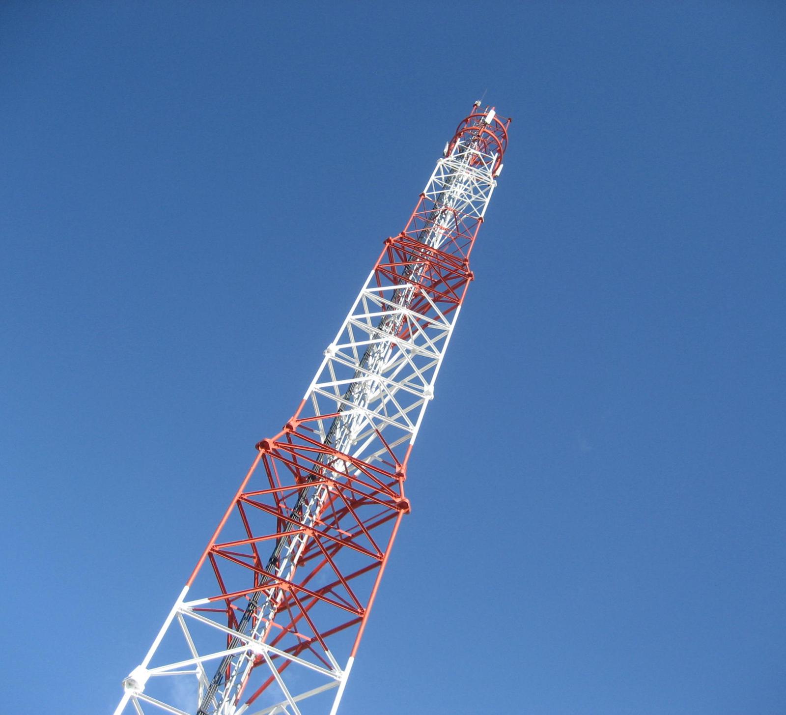 Red and white self-supporting tower against a blue sky